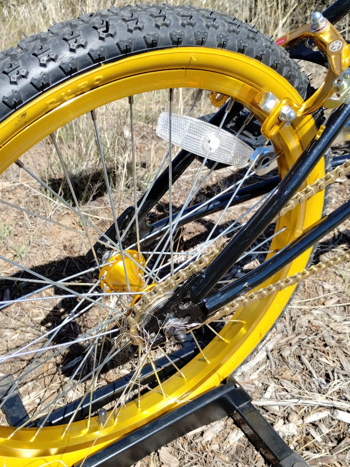 Close-up of a kuwahara KZ-01 bicycle wheel with gold and black tire on a natural background